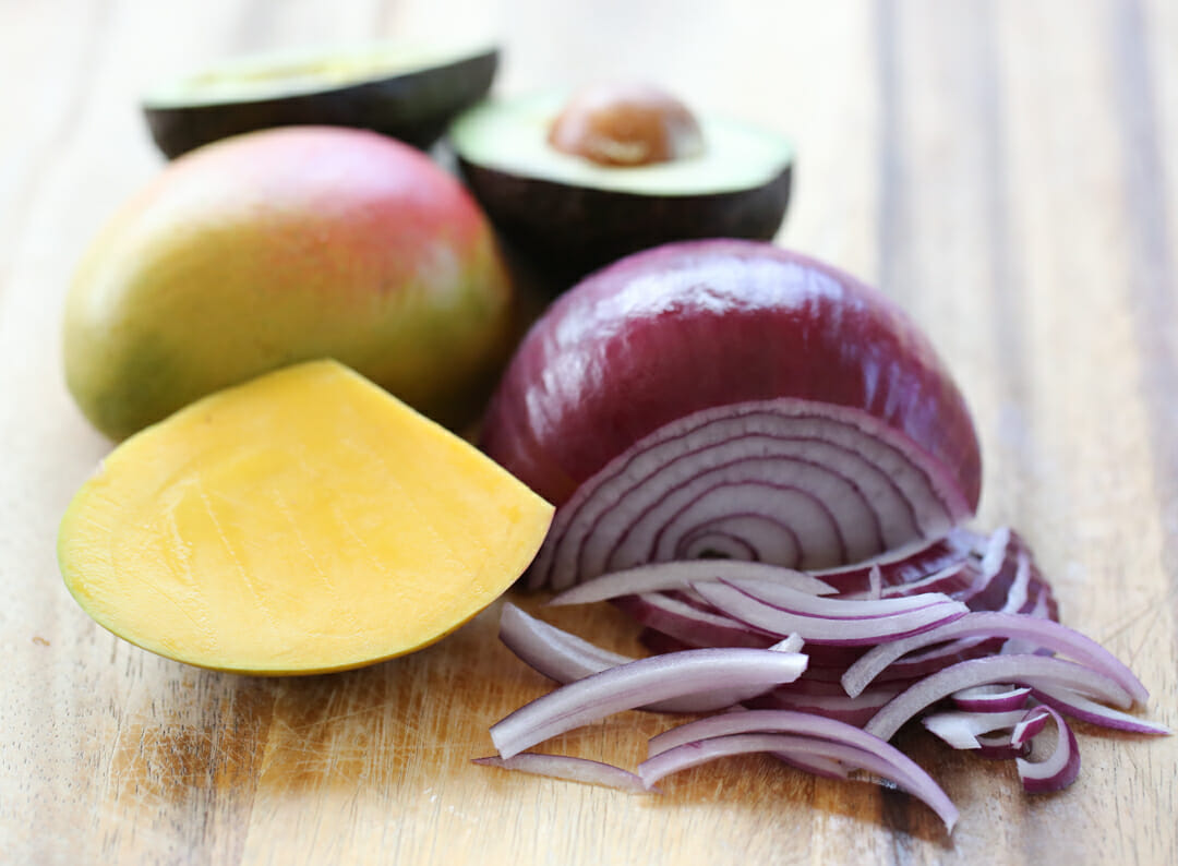 mango, onion, and avocado on cutting board