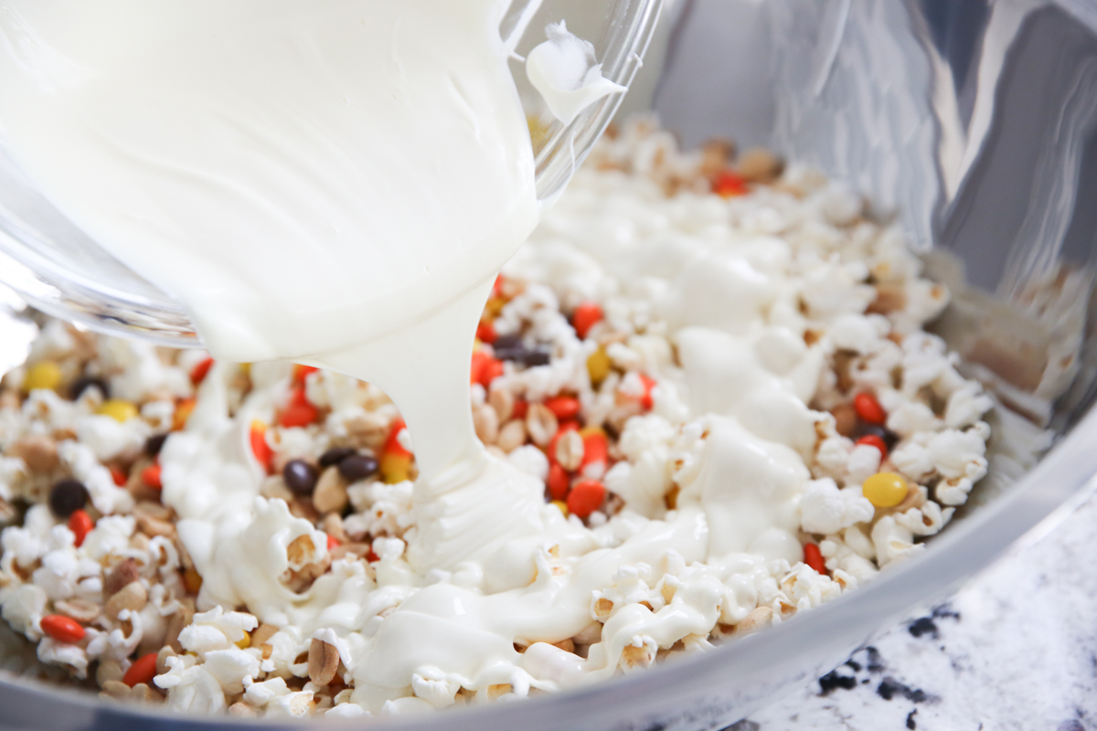 Pouring Almond Bark over a bowl of popcorn and candy