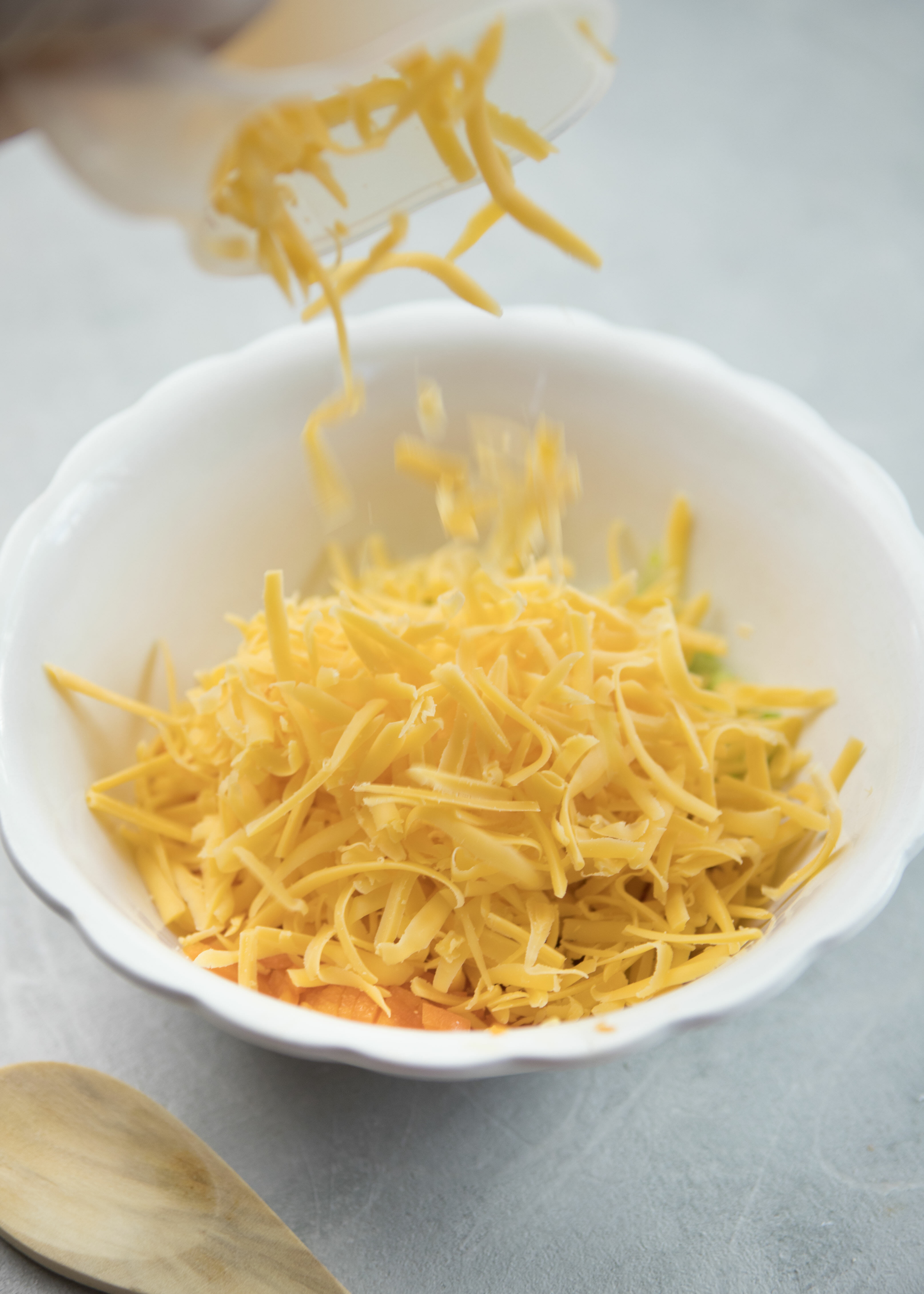 adding shredded cheddar cheese to Perfect Cheeseball