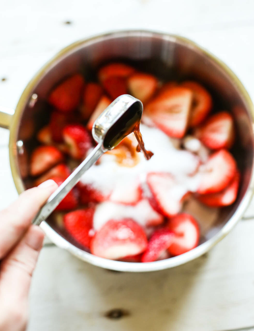 adding vanilla to sliced strawberries and sugar