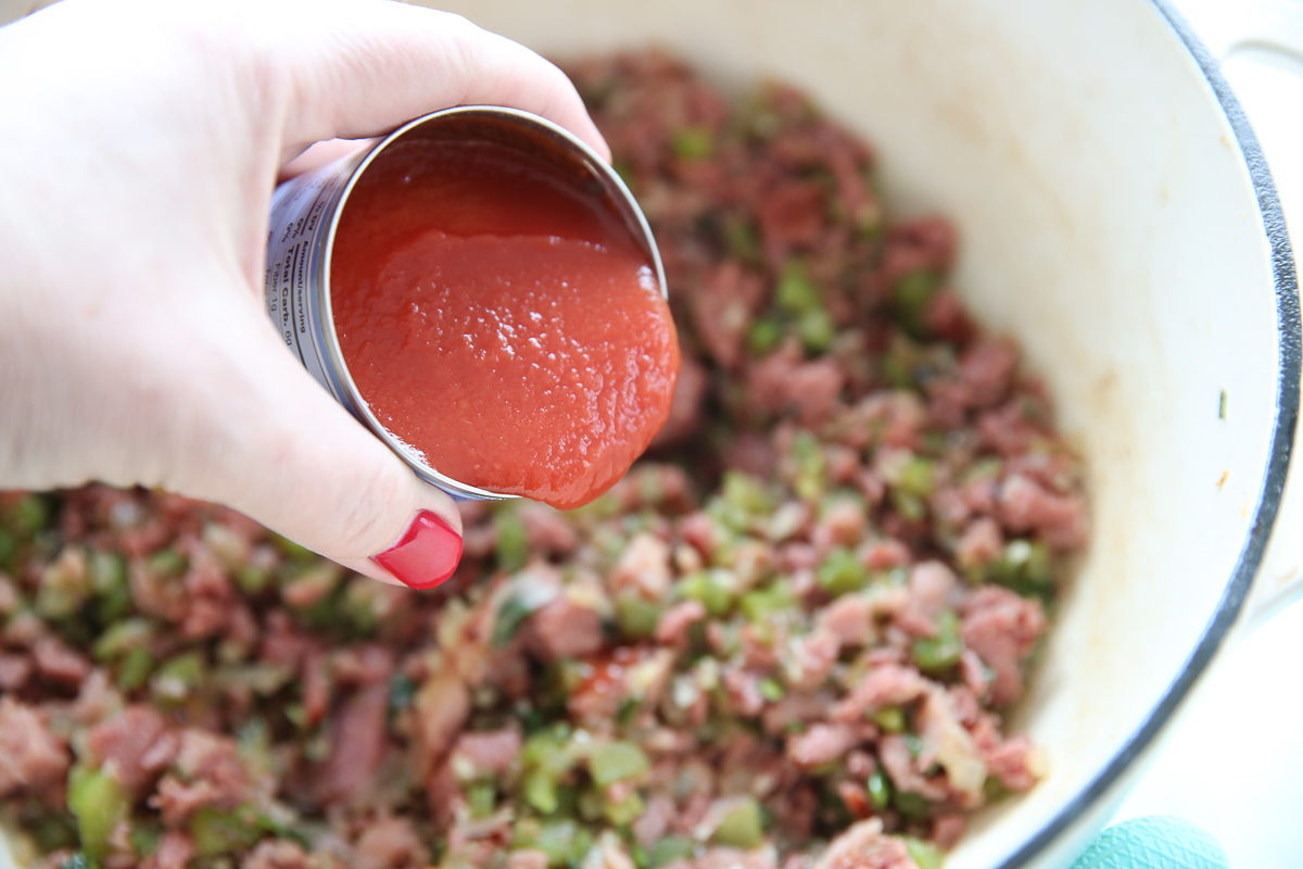pouring tomato sauce into jambalaya