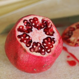 A pomegranate with the top cut off and arils visible inside.