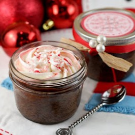 A peppermint fudge cupcake baked right into a little jar, topped with peppermint frosting and candy cane pieces.