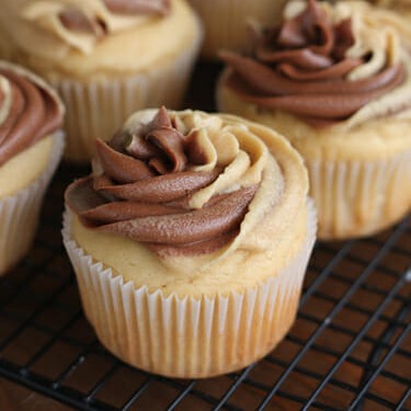 Swirled peanut butter and chocolate frosting on top of a cupcake, with more cupcakes in the background.