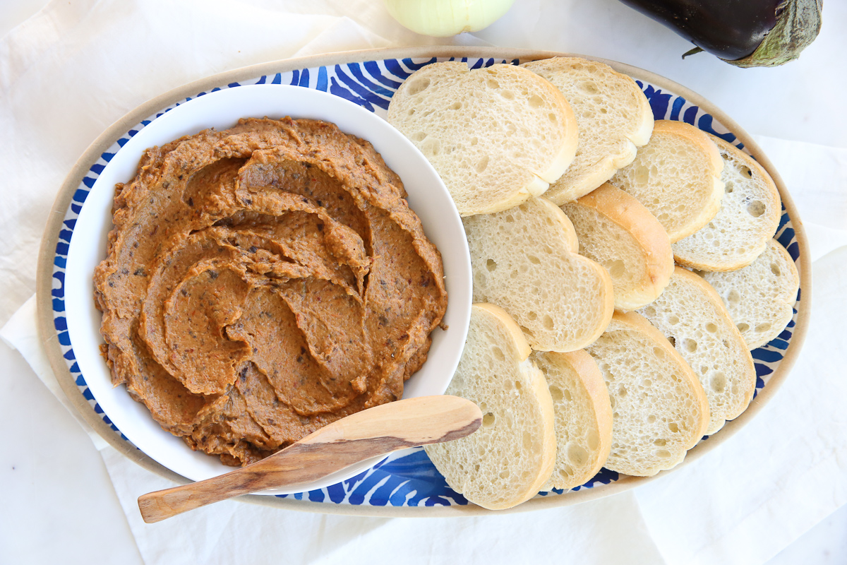 Eggplant spread in a white bowl with a spreader