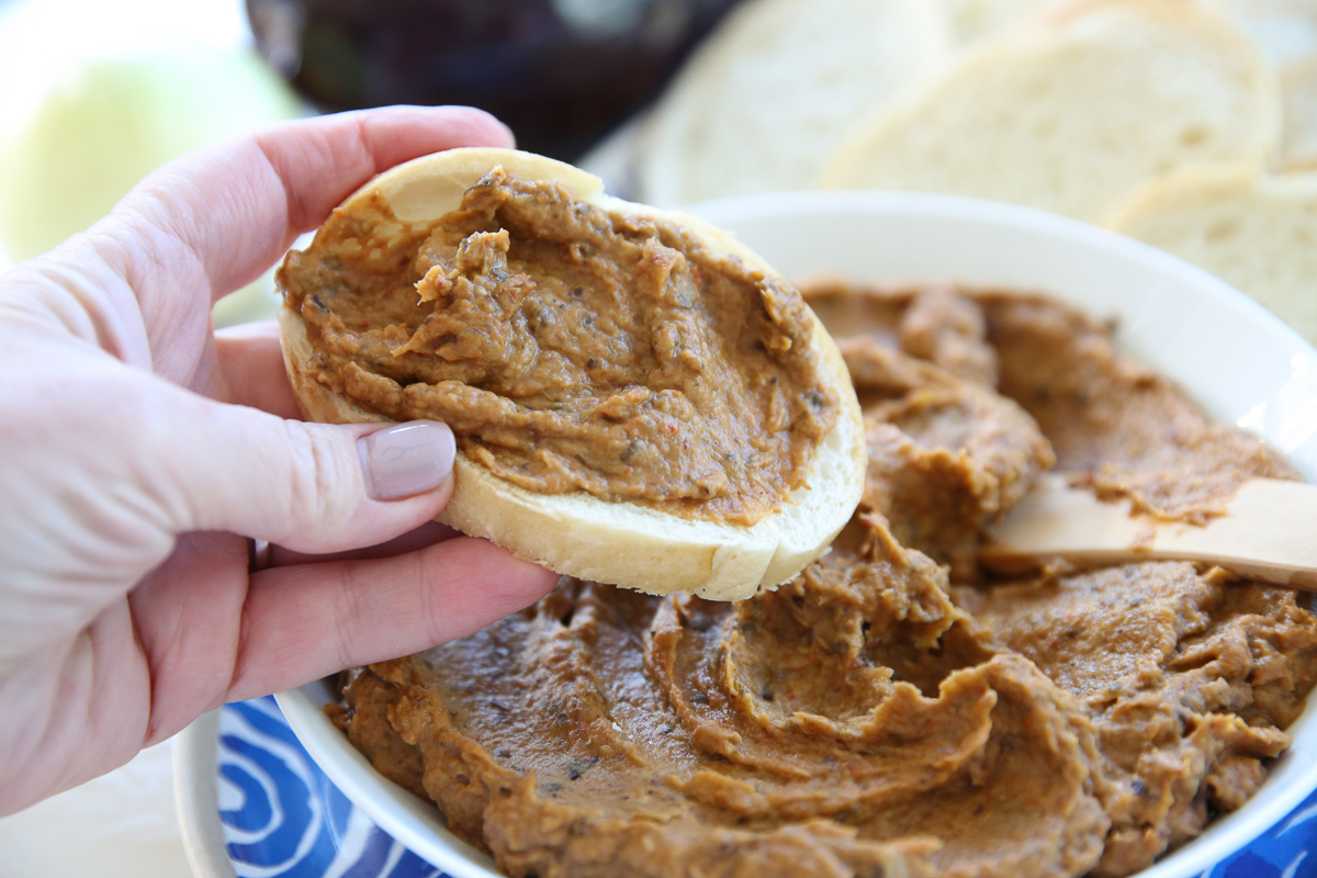 spreading eggplant dip on a slice of bread