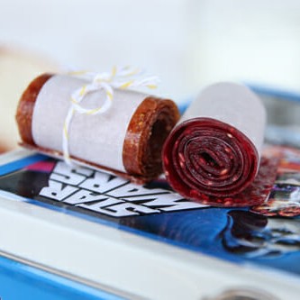 A couple of homemade fruit roll ups, wrapped in parchment and tied with string, sitting on top of a Star Wars lunch box.