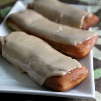 3 maple bar donuts lined up on a white serving platter.