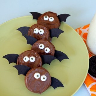 A plate of cute little bats made from chocolate dipped oreos with candy eyes and paper wings.
