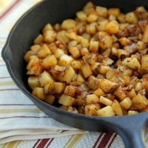 A cast iron skillet full of cubed breakfast potatoes.