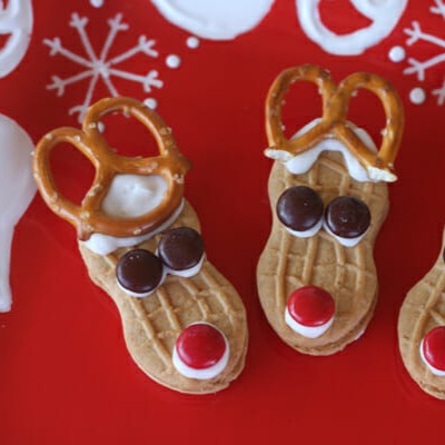 Reindeer cookies made from nutter butters, with mini M&Ms for eyes and noses and a mini pretzel for antlers.