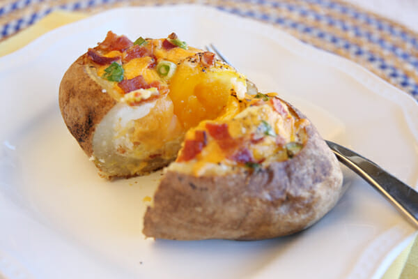 cut stuffed baked potato served on plate