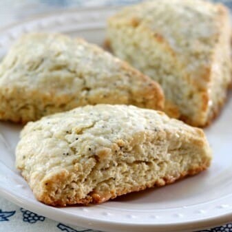3 lemon poppyseed scones on a white serving plate.