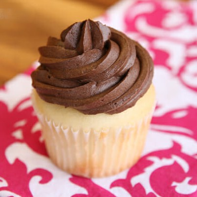 A vanilla cupcake with chocolate frosting swirled on top.