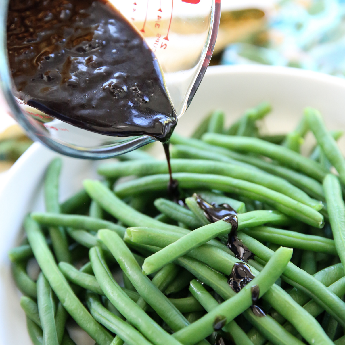 pouring balsamic reduction over beans