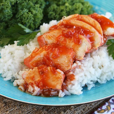 Sliced chicken breast in a sweet, red sauce, layered over rice with a side of broccoli.