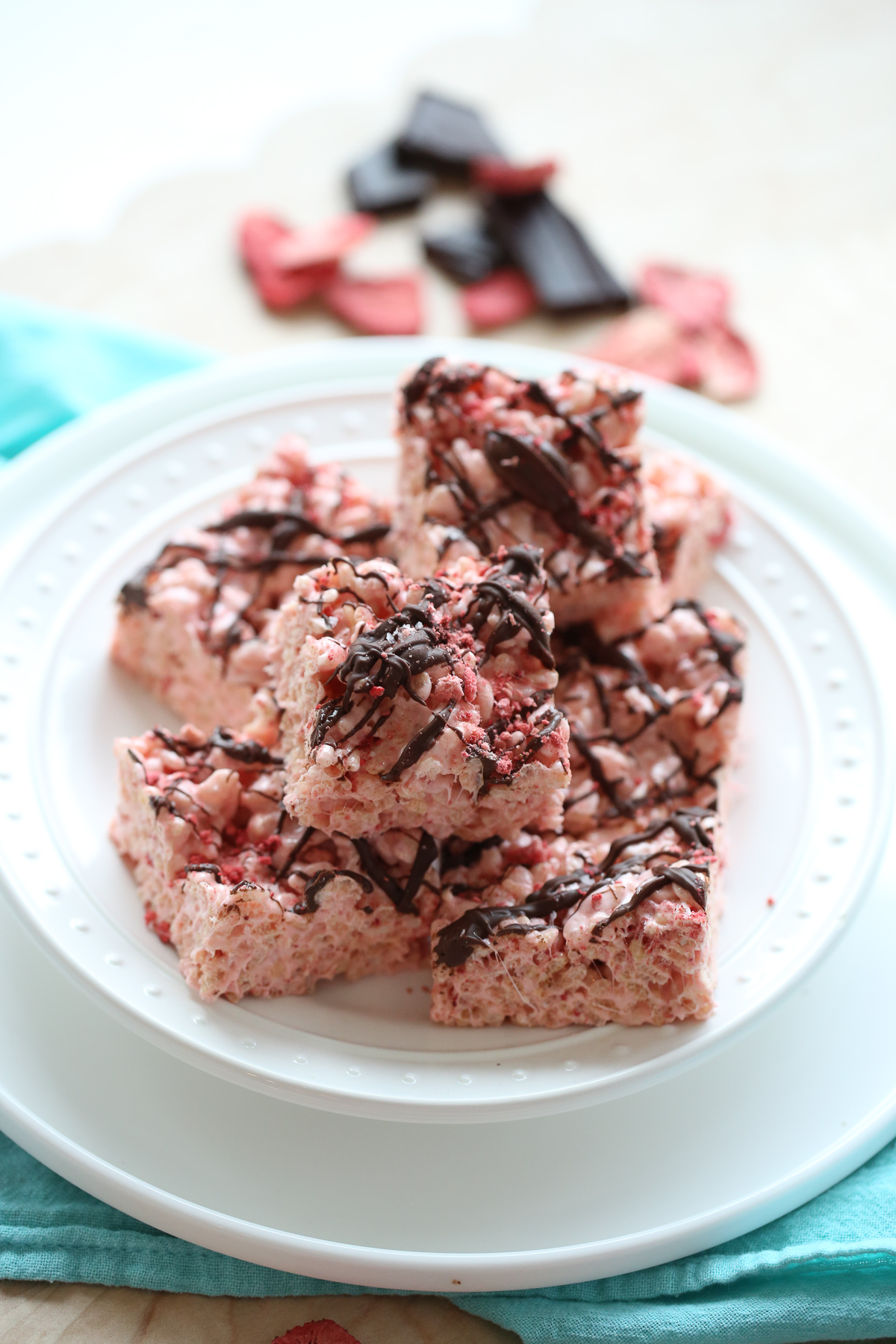 pink rice krispie treats in a pan drizzled with chocolate and berries