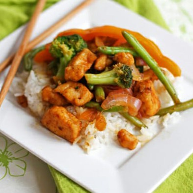 A plate with chopsticks, rice, and a serving of chicken stir fry with vegetables.