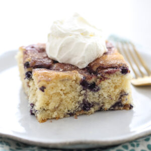 blueberry coffee cake on a plate with whipped cream