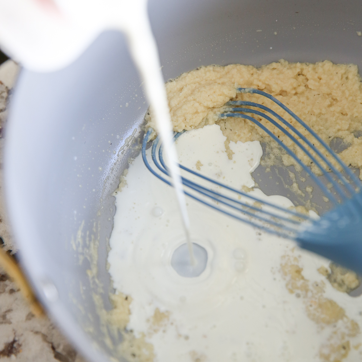 pouring half and half into a pan with flour and butter