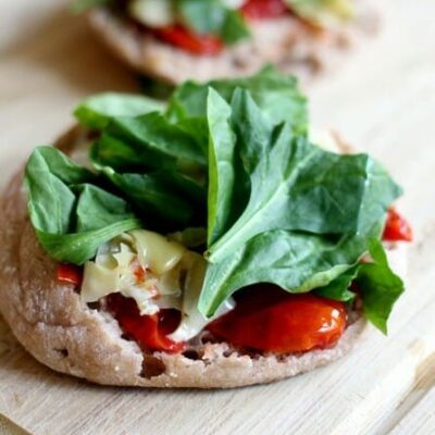 An English muffin topped with roasted red peppers, cheese, and spinach.