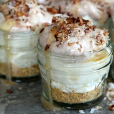 A layered samoa cream pie in a jar. There's a layer of graham cracker crust, then a creamy filling, topped with caramel and toasted coconut.
