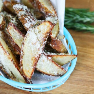 A basket of wedge-style homemade French fries with parmesan and rosemary.
