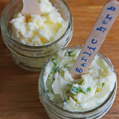 Two little jars of homemade butter. One has a label that says, "garlic herb."