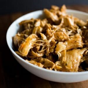 A white bowl filled with shredded taco-seasoned chicken.