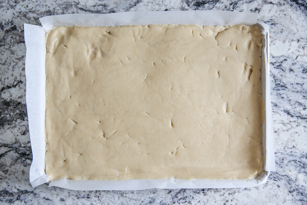 Sugar cookie dough pressed into a baking sheet