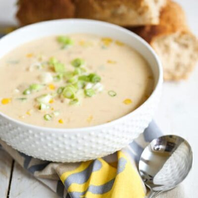 A white bowl filled with creamy crawfish and corn bisque, topped with green onions.