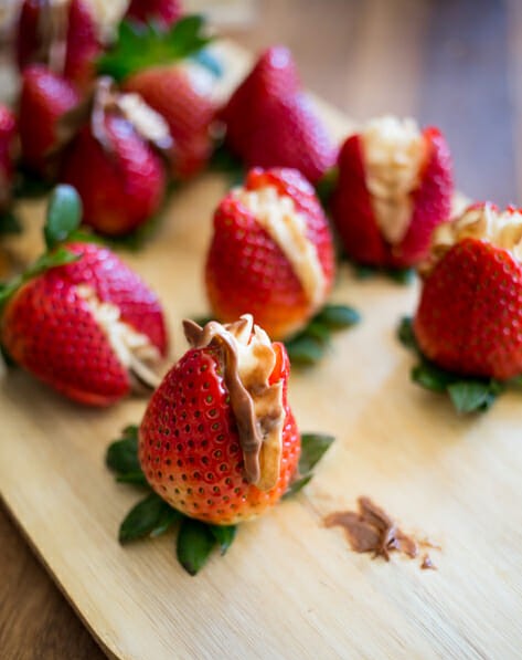 A strawberry stuffed with hazelnut cream cheese filling on a cutting board.