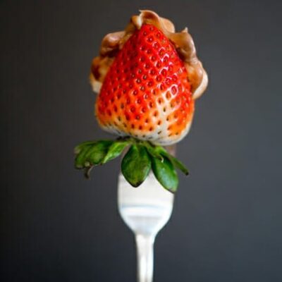 A strawberry on a fork. The inside is stuffed with hazelnut cream.