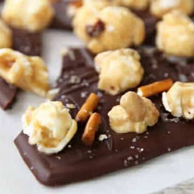 A piece of easy gourmet chocolate bark topped with caramel corn, pretzels, and sea salt.