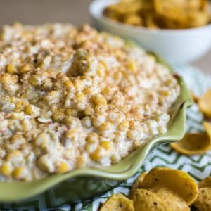 A bowl of chile cheese corn dip, surrounded by Fritos chips.