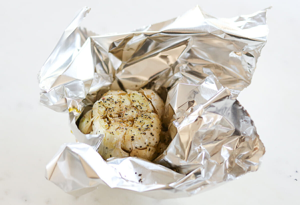 A head of garlic, wrapped in foil to be roasted