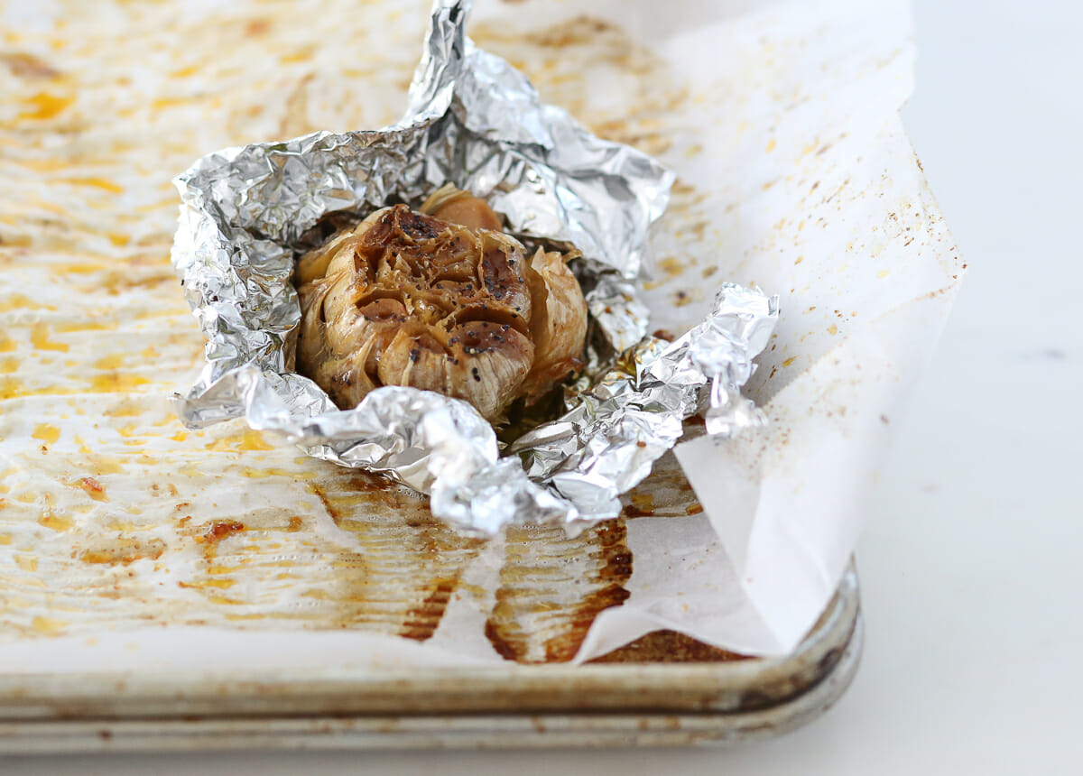 A head of garlic, roasted and wrapped in a piece of foil.
