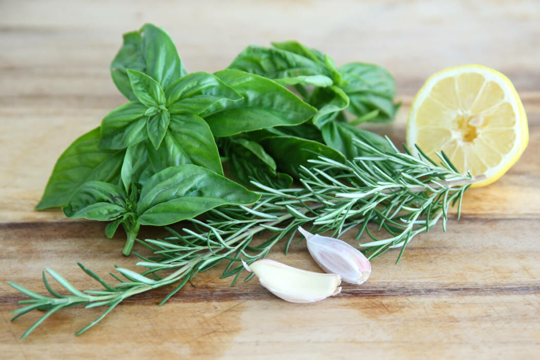 Fresh herbs, lemon, and garlic on a cutting board.