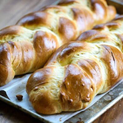 Two loaves of challah on a bread baking pan.