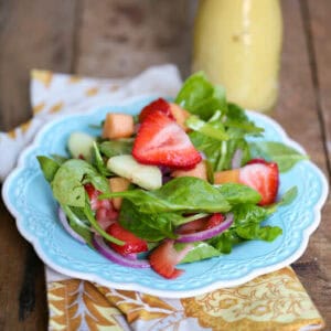 A strawberry cucumber and melon salad on a blue plate.