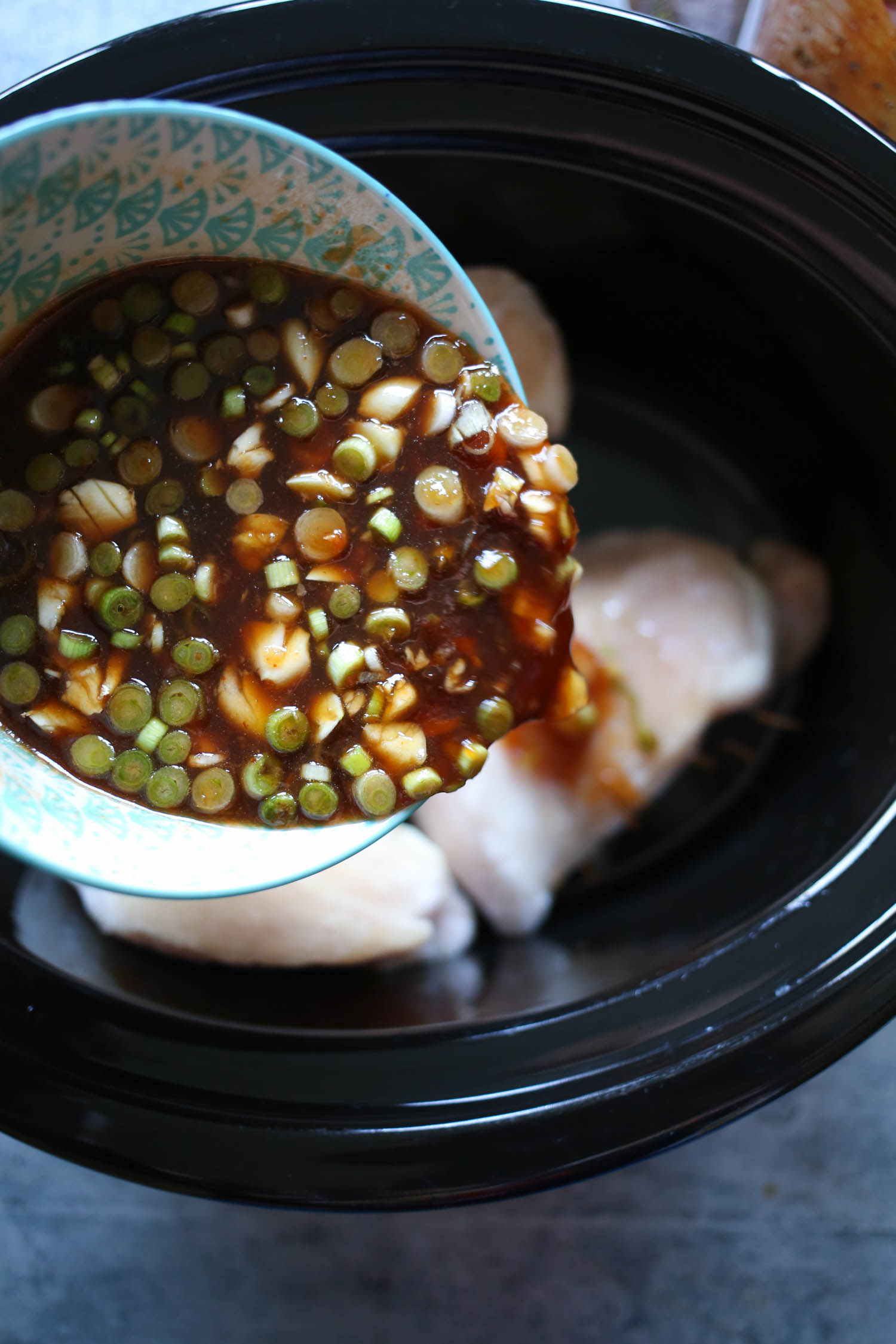 pouring sauce over chicken breasts in slow cooker honey garlic chicken