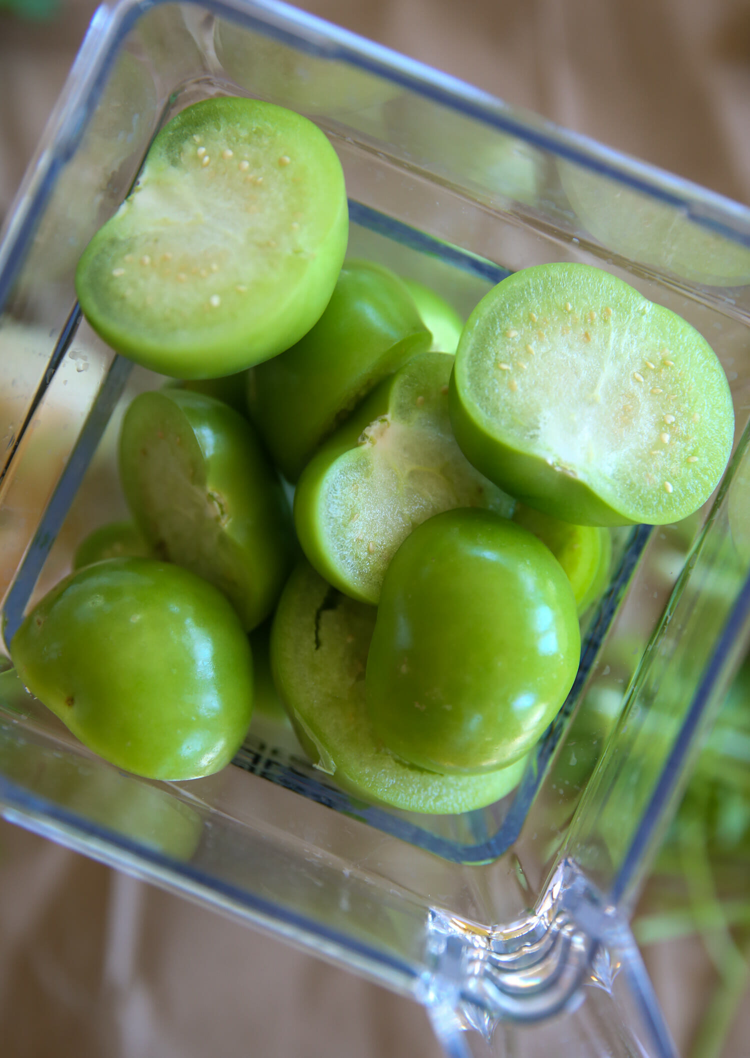 sliced tomatillos in a blender for avocado salsa verde from our best bites