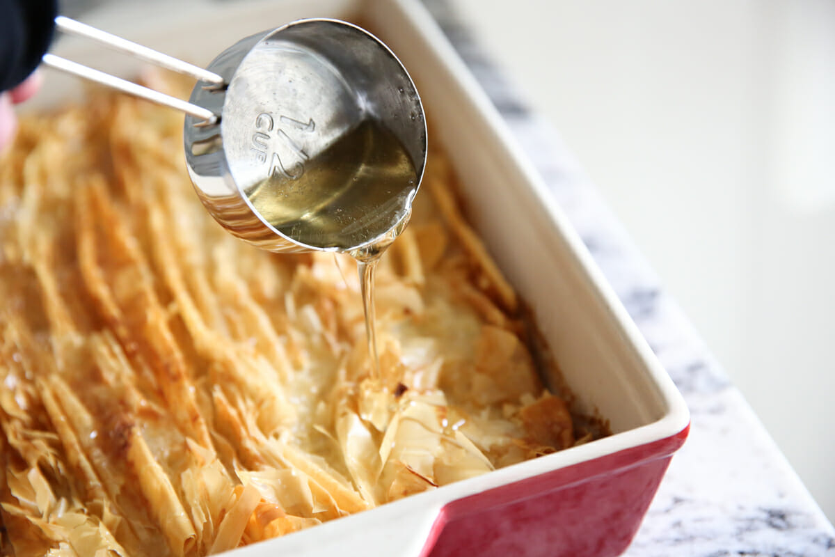 pouring sugar syrup over phyllo dough