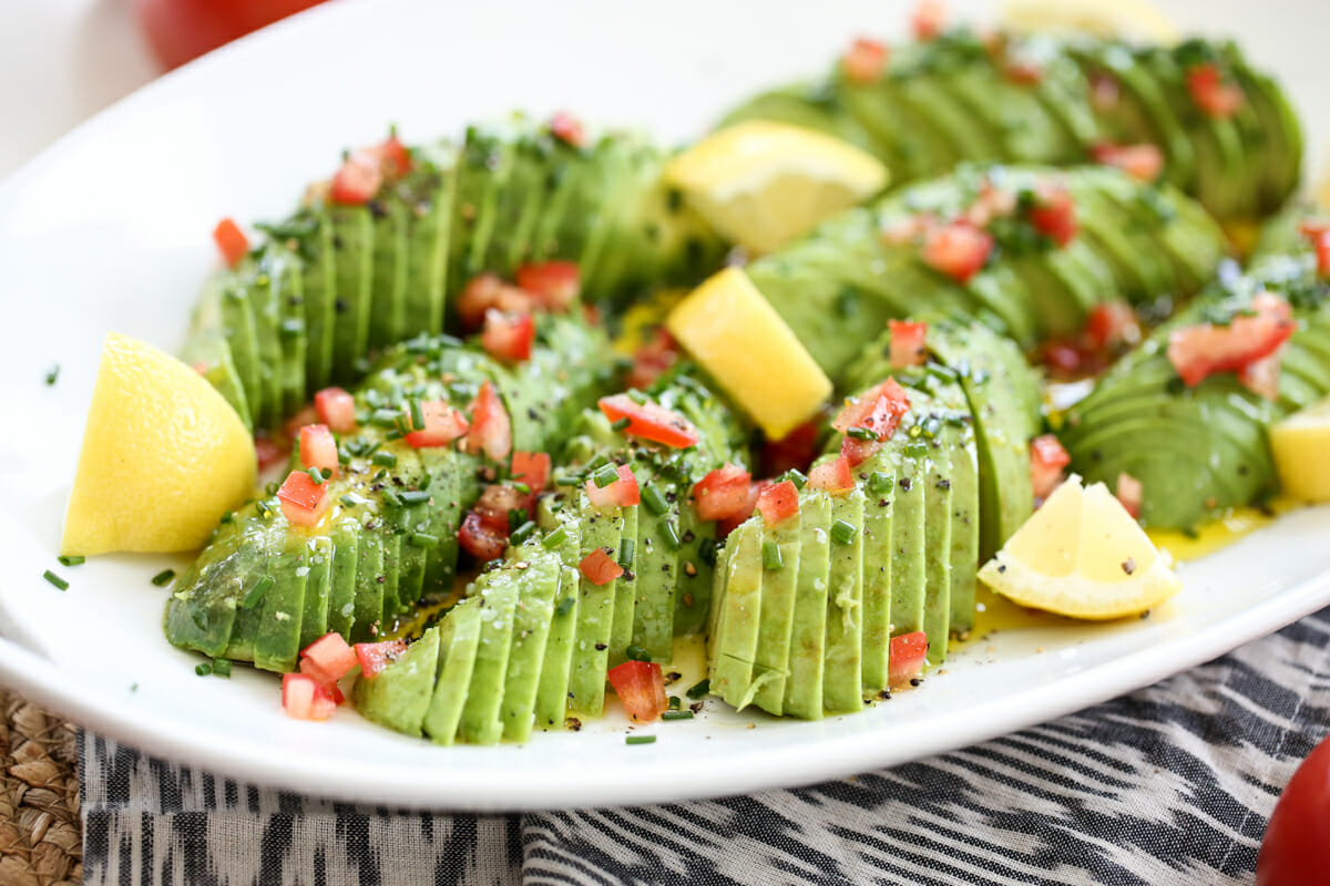 thinly sliced avocados on a platter with lemon wedges