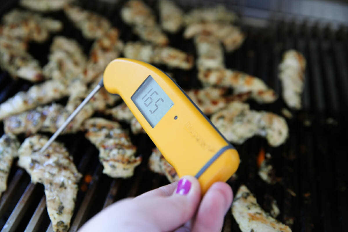 Checking the temperature of chicken on the grill with a digital thermometer