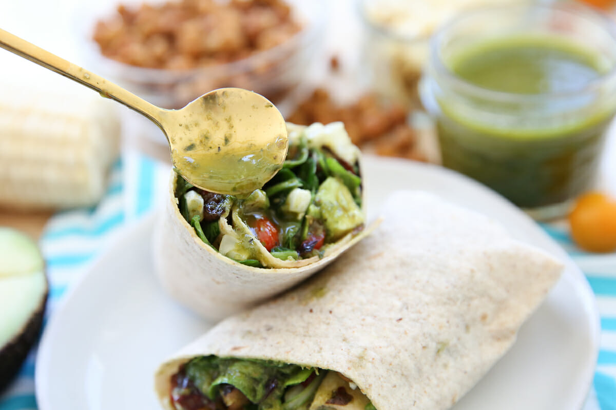 Drizzling dressing on the inside of a veggie wrap.