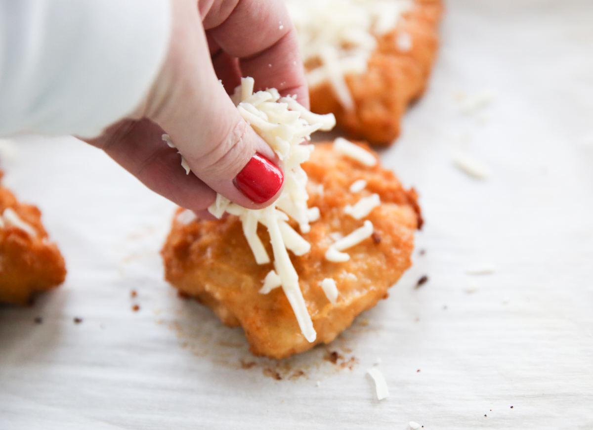 adding cheese to breaded chicken