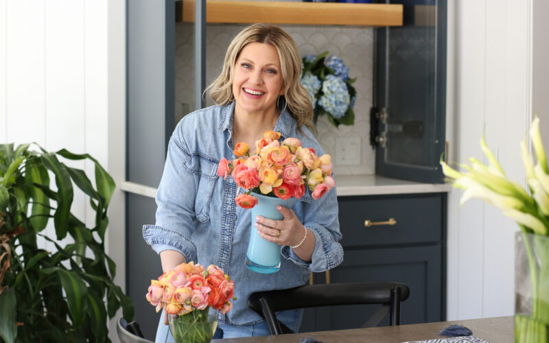 woman in denim shirt holding flowers