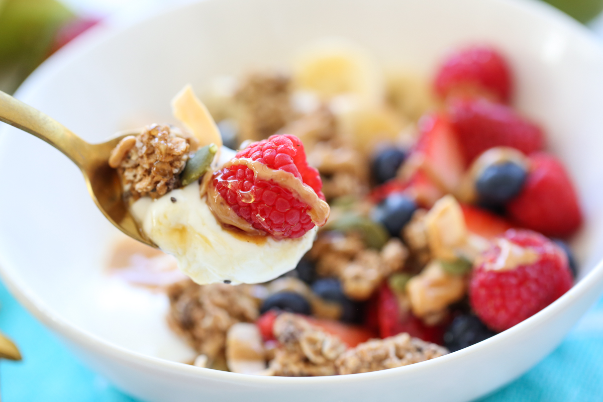 spoonful of yogurt with a berry and granola