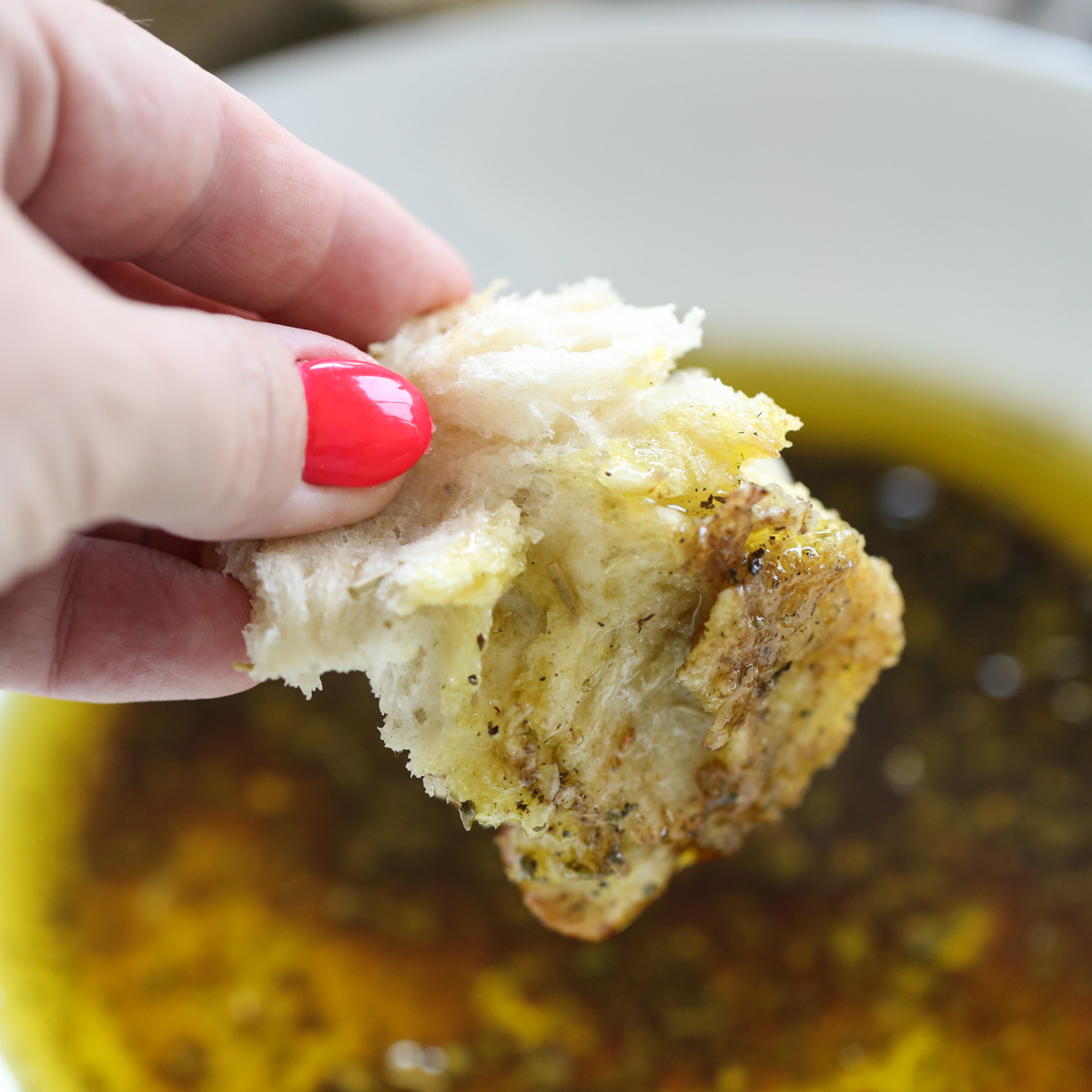 dipping chunk of bread into olive oil